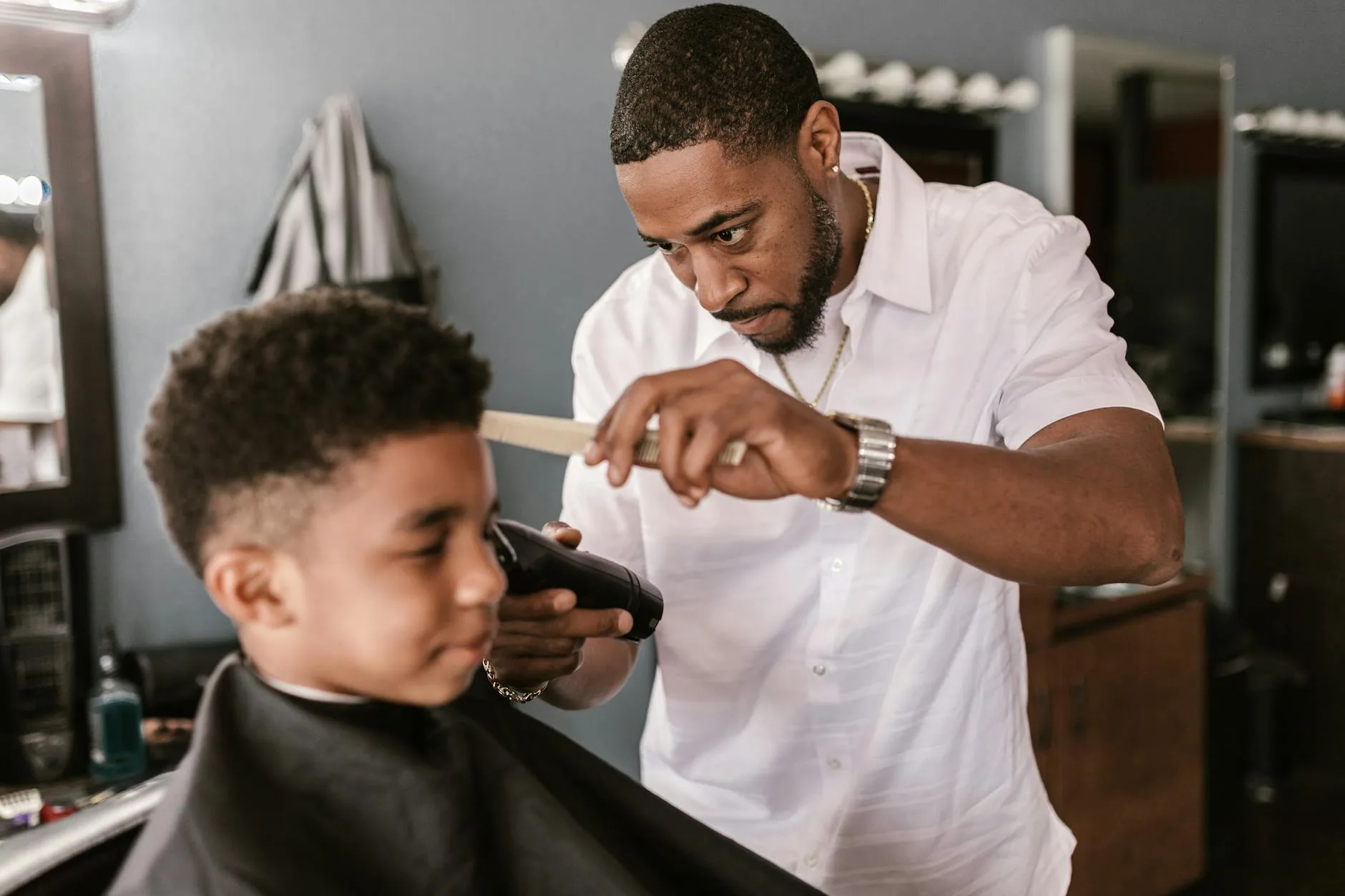 Barber apprentice learning clipper technique from an instructor